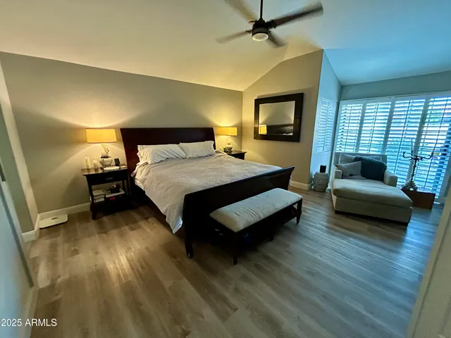 a spacious bedroom with a bed a couch and a flat tv screen on dresser