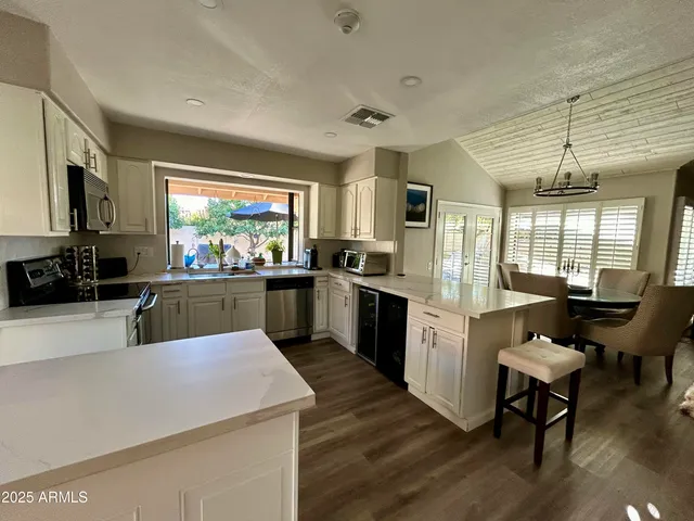 a kitchen with granite countertop a stove a sink a dining table and chairs