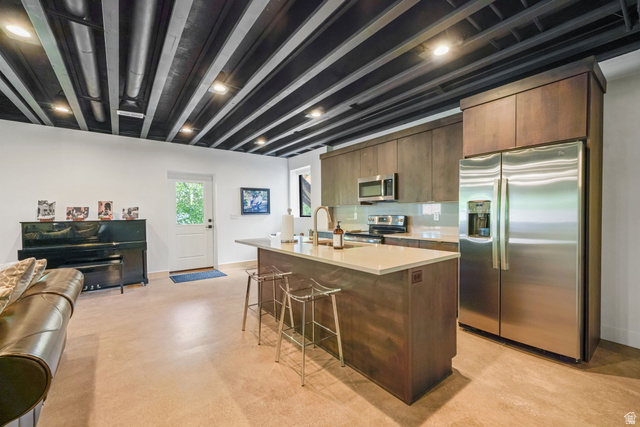 3667 Little Cottonwood Road, Unit 1 Sandy, UT 84092 - Photo 27 of 49 Modern kitchen featuring stainless steel appliances, a center island with countertop seating, and wood-finish cabinetry