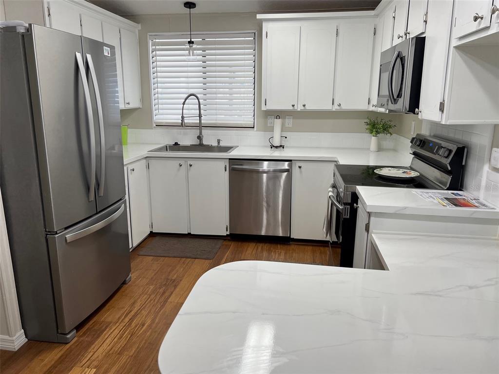 1001 Starkey Road, Unit 177 Largo, FL 33771 - Photo 5 of 44 a kitchen with stainless steel appliances a refrigerator sink and wooden cabinets