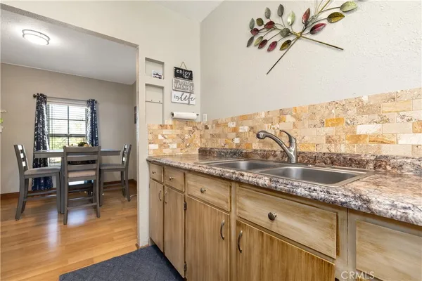 a kitchen with granite countertop a stove a sink and dining table with wooden floor