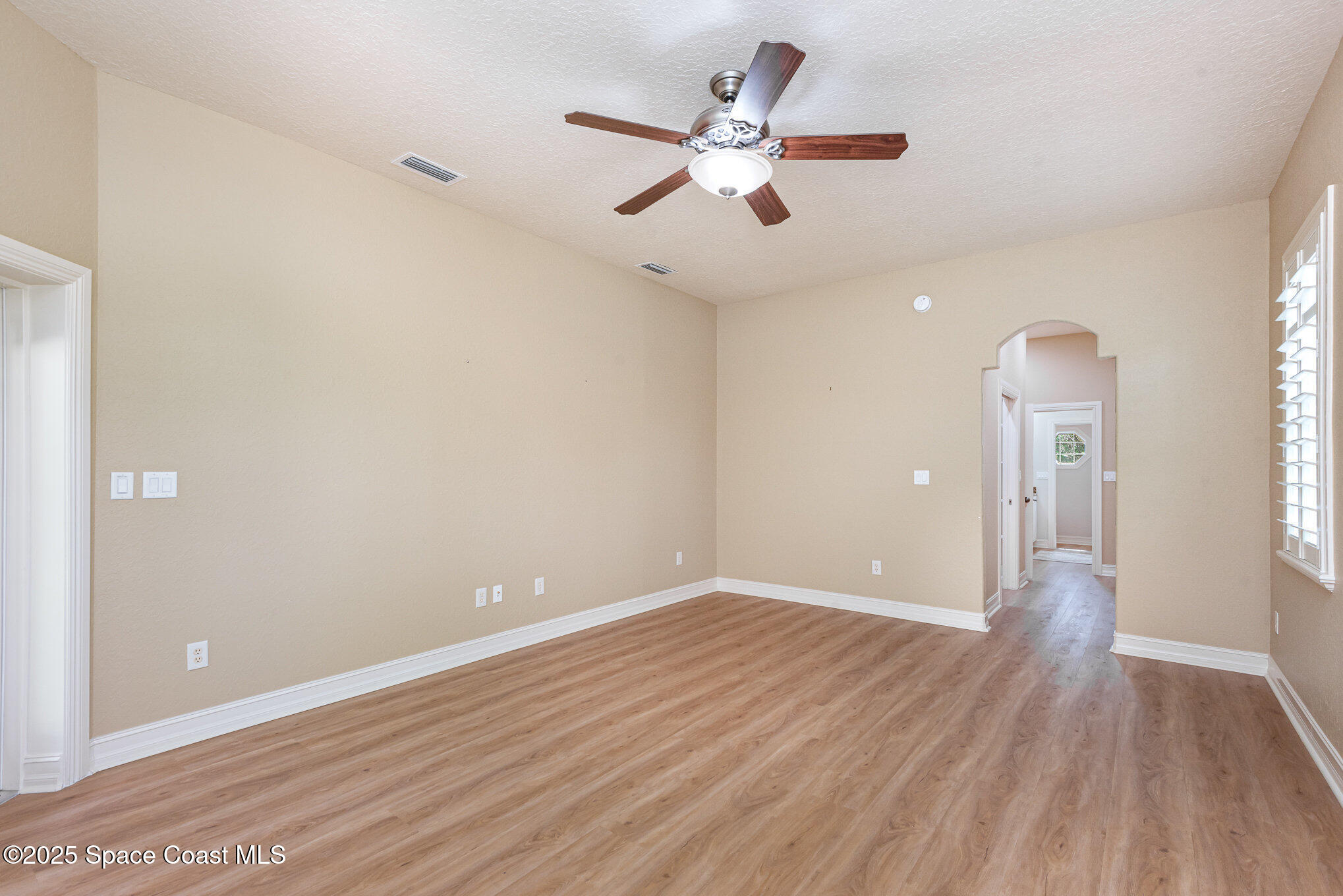 3260 Quantum Place Mims, FL 32754 - Photo 18 of 43 an empty room with wooden floor and a ceiling fan