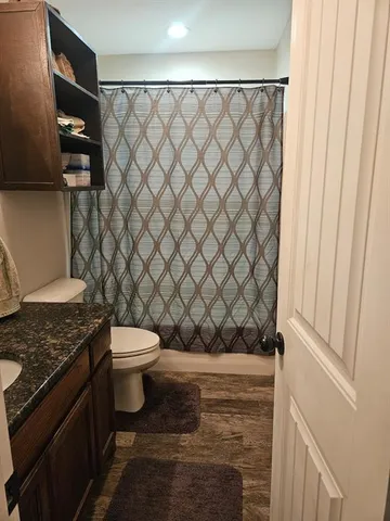 a bathroom with a granite countertop toilet and a sink
