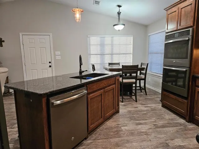 a kitchen with stainless steel appliances granite countertop a stove a sink and a refrigerator