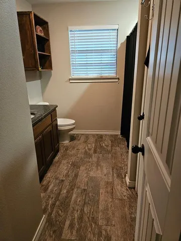 a bathroom with a sink a toilet a window and vanity