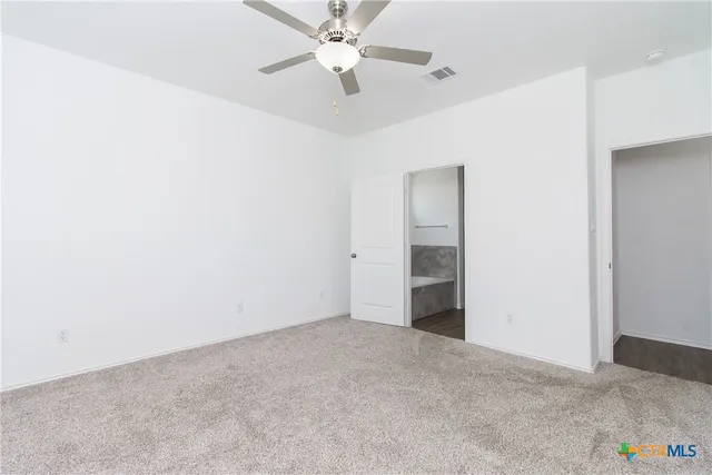 an empty room with closet and a ceiling fan