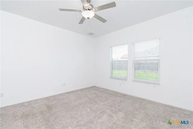 an empty room with a window and a fan