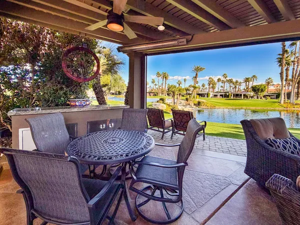 a view of a dining room with furniture one side kitchen view and wooden floor