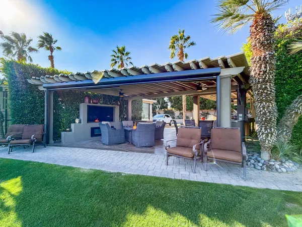 a view of a patio with table and chairs potted plants and a palm tree