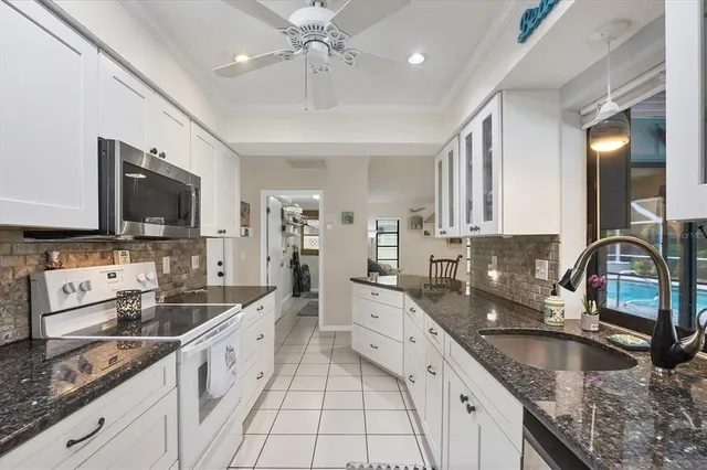 a large kitchen with granite countertop a sink a counter top space appliances and cabinets