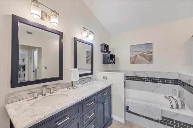 a bathroom with a bathtub a double vanity sink and a mirror