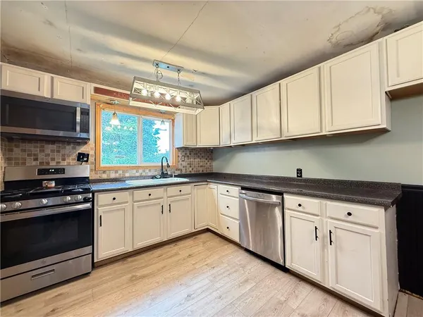 a kitchen with granite countertop a refrigerator a sink a stove top oven and cabinetry