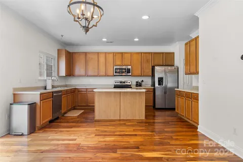 a kitchen with stainless steel appliances granite countertop a refrigerator a sink dishwasher a stove with wooden cabinets and floor