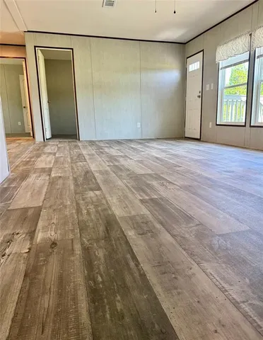 a view of a big room with wooden floor and windows