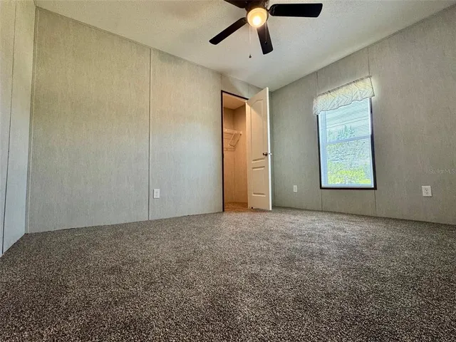 an empty room with ceiling fan and windows