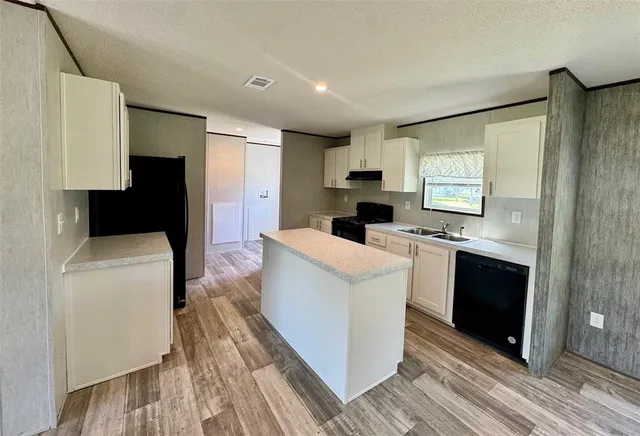 a kitchen with a sink a refrigerator and cabinets