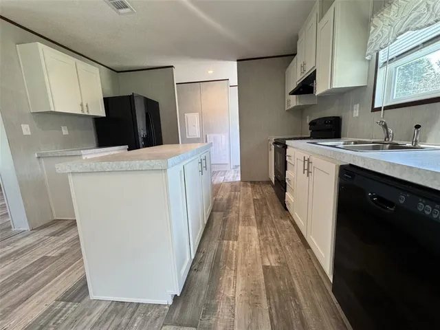 a kitchen with a sink a refrigerator a stove top oven and wooden floor