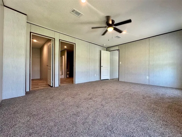 an empty room with ceiling fan and windows