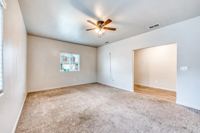 an empty room with windows and fan