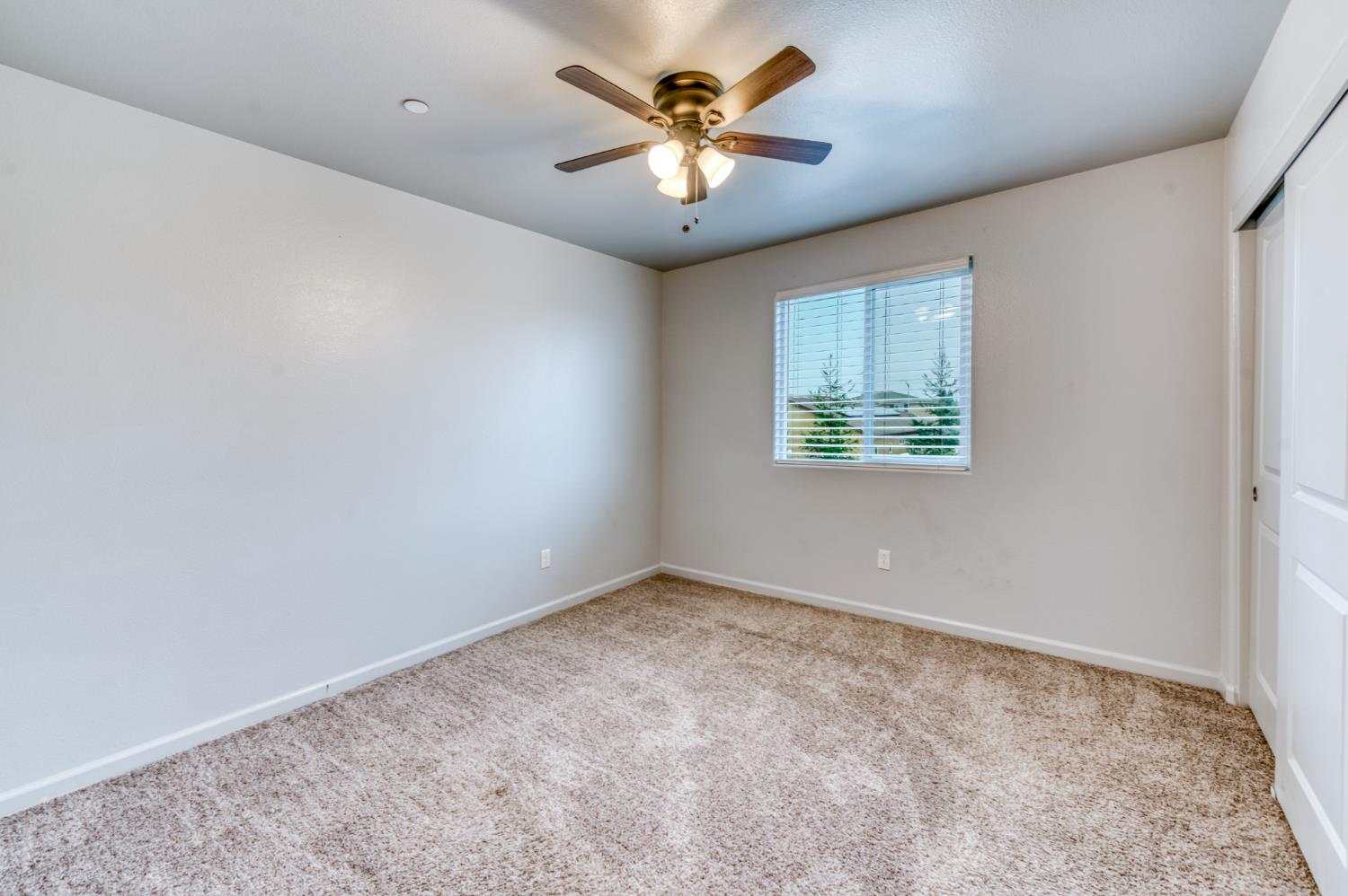 1391 Shoreside Drive Madera, CA 93637 - Photo 5 of 30 an empty room with windows and a chandelier fan