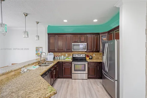 a kitchen with stainless steel appliances granite countertop a sink stove refrigerator and cabinets
