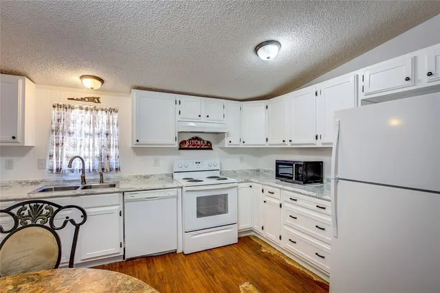 a kitchen with granite countertop a sink cabinets stainless steel appliances and a counter space