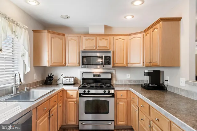 a kitchen with stainless steel appliances granite countertop a sink a stove a microwave and cabinets