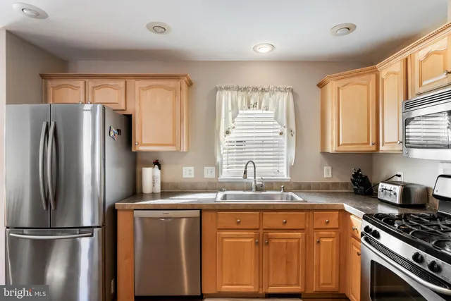 a kitchen with granite countertop cabinets stainless steel appliances a sink and a window