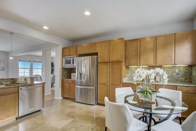 a kitchen with stainless steel appliances granite countertop a refrigerator a table and chairs