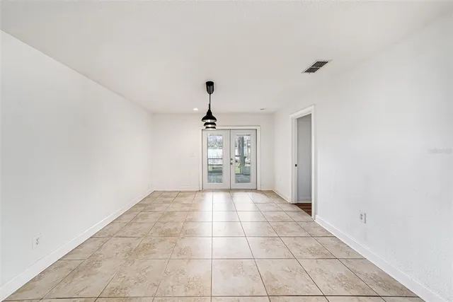 a view of an empty room with window and chandelier fan