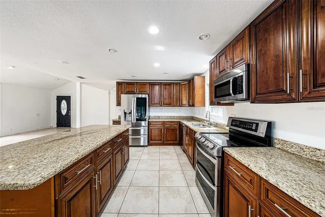 a large kitchen with stainless steel appliances granite countertop a stove refrigerator and microwave