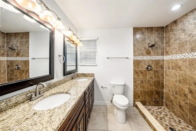 a bathroom with a granite countertop toilet a sink a shower and a mirror
