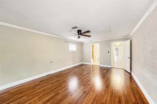 a view of empty room with wooden floor and ceiling fan