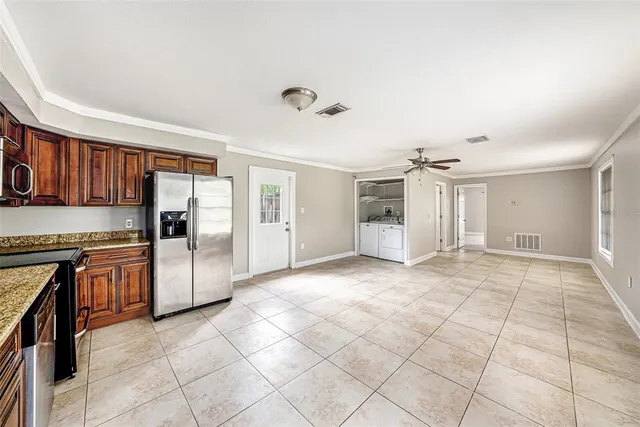 a large kitchen with stainless steel appliances kitchen island granite countertop a refrigerator and a sink