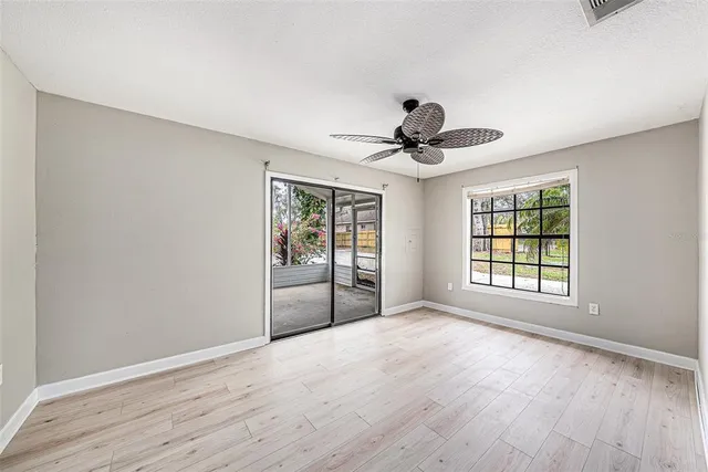 an empty room with wooden floor and ceiling fan
