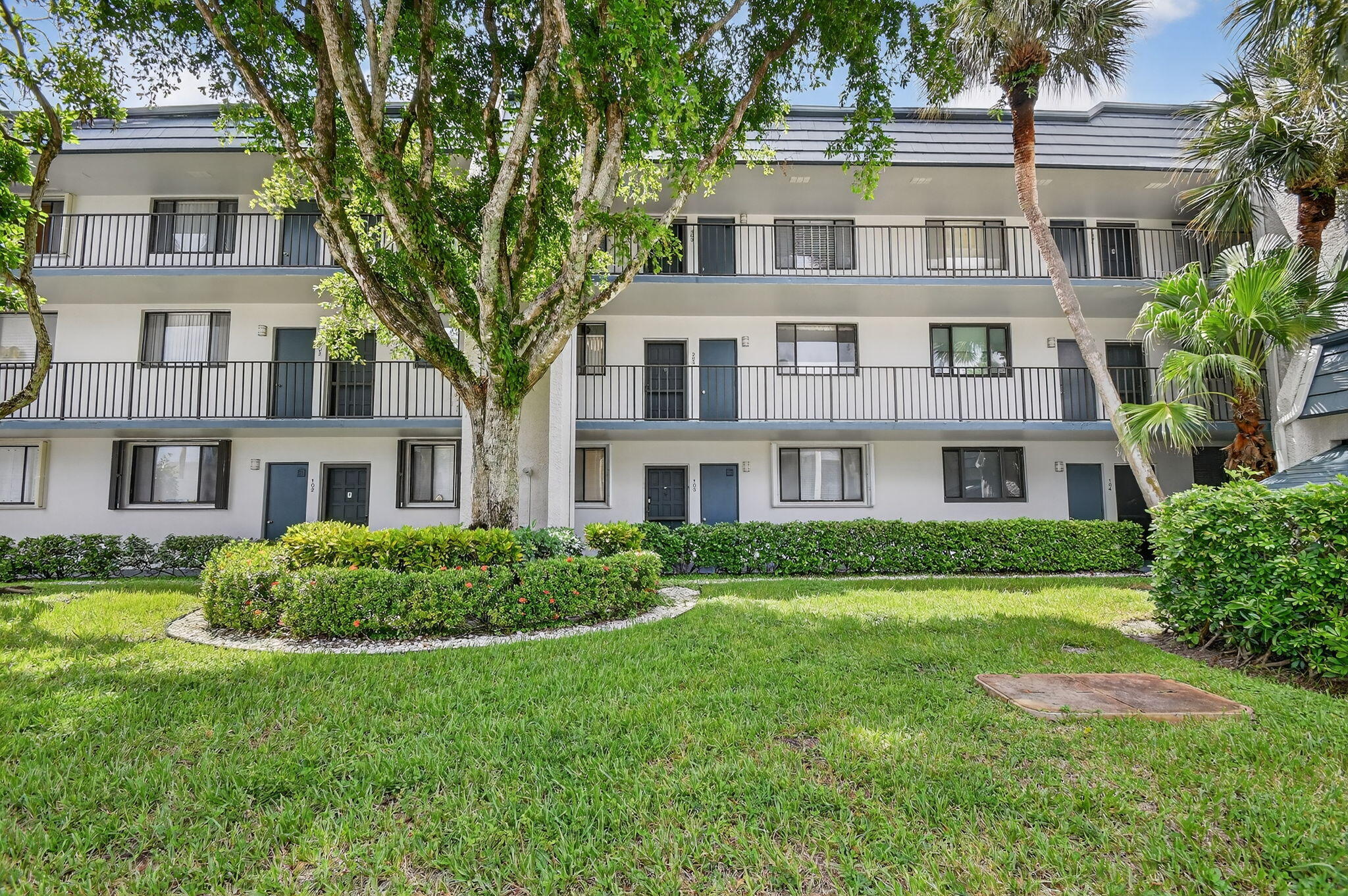 4381 Trevi Court, Unit 303 Lake Worth, FL 33467 - Photo 2 of 80 a front view of a residential apartment building with a yard