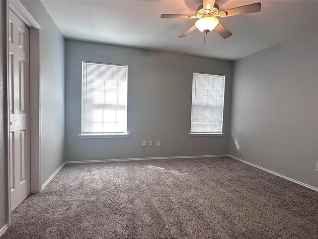 a view of an empty room with window and chandelier fan