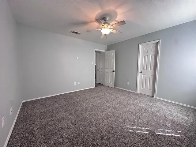 a view of an empty room with chandelier fan