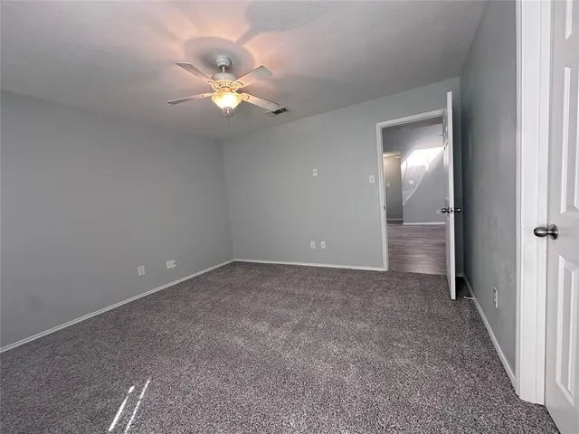 a view of an empty room with a chandelier fan