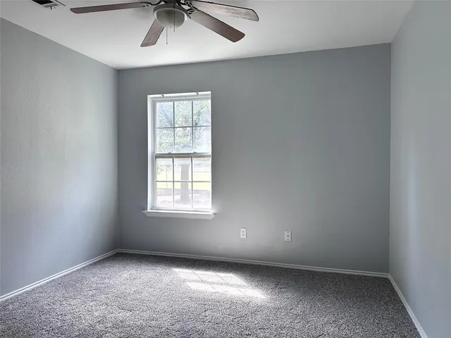 an empty room with a window and a ceiling fan
