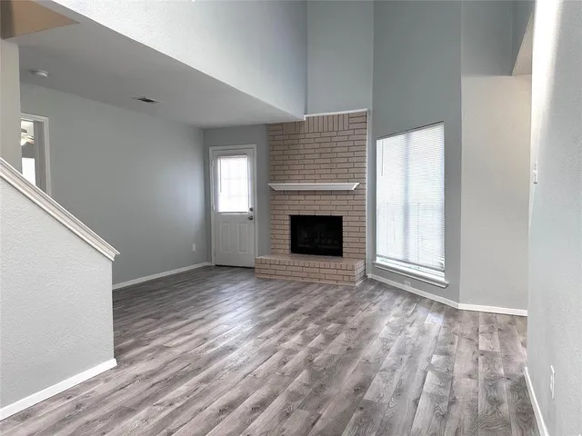 an empty room with wooden floor fireplace and windows