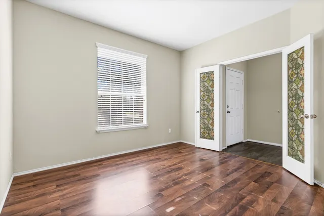 a view of an empty room with wooden floor and a window