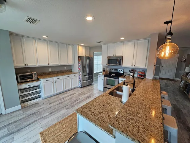 a kitchen with stainless steel appliances granite countertop a sink refrigerator and cabinets