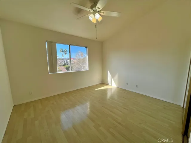 an empty room with a fan & a window