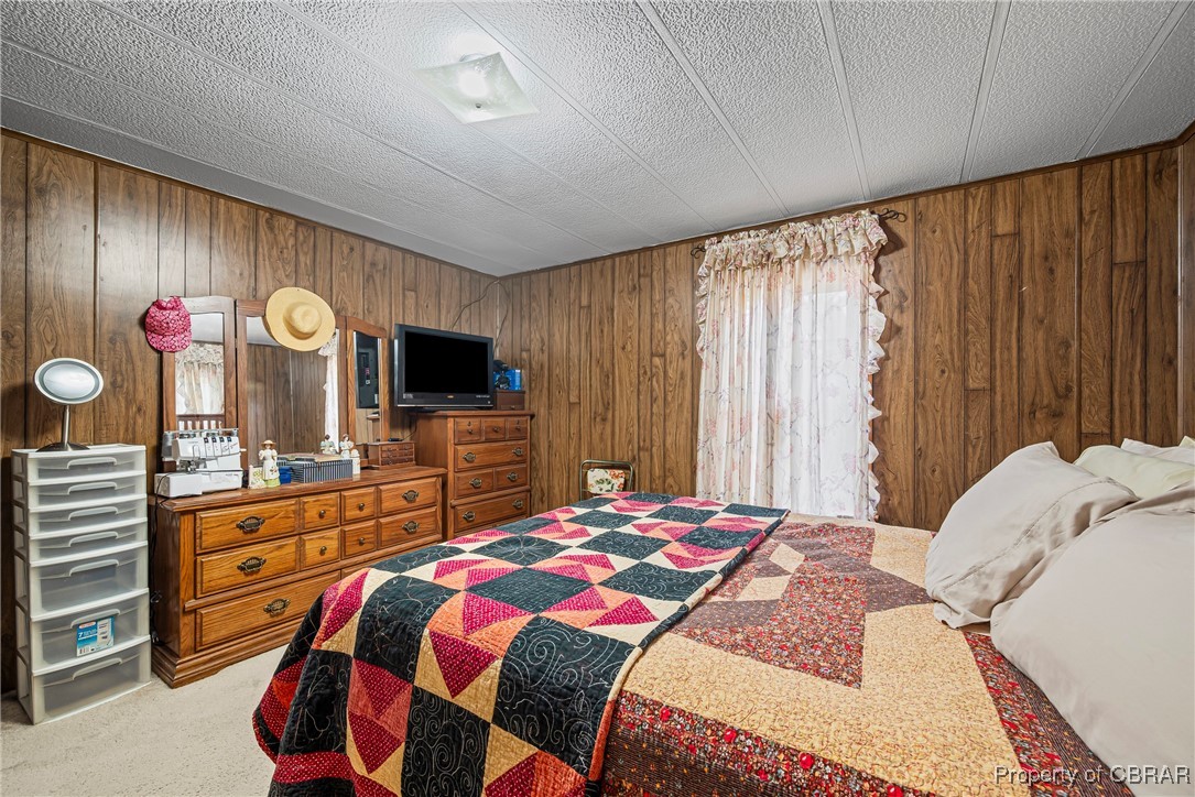 8633 Guinea Road Hayes, VA 23072 - Photo 22 of 30 Bedroom featuring a textured ceiling, wood walls, and carpet flooring