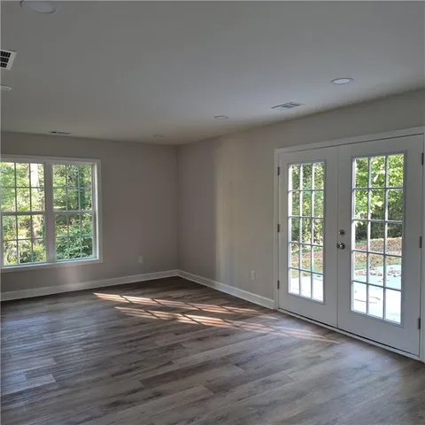 a view of an empty room with wooden floor and a window