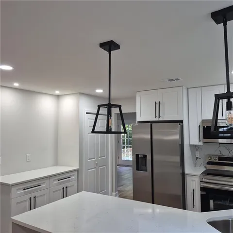 a kitchen with stainless steel appliances kitchen island granite countertop a sink and a refrigerator