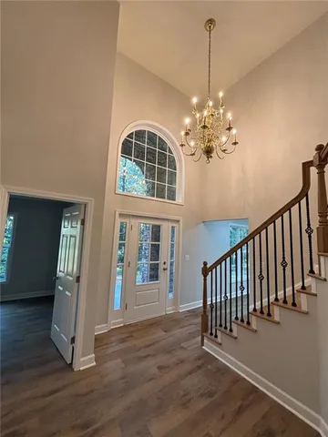 an empty room with wooden floor chandelier fan and windows