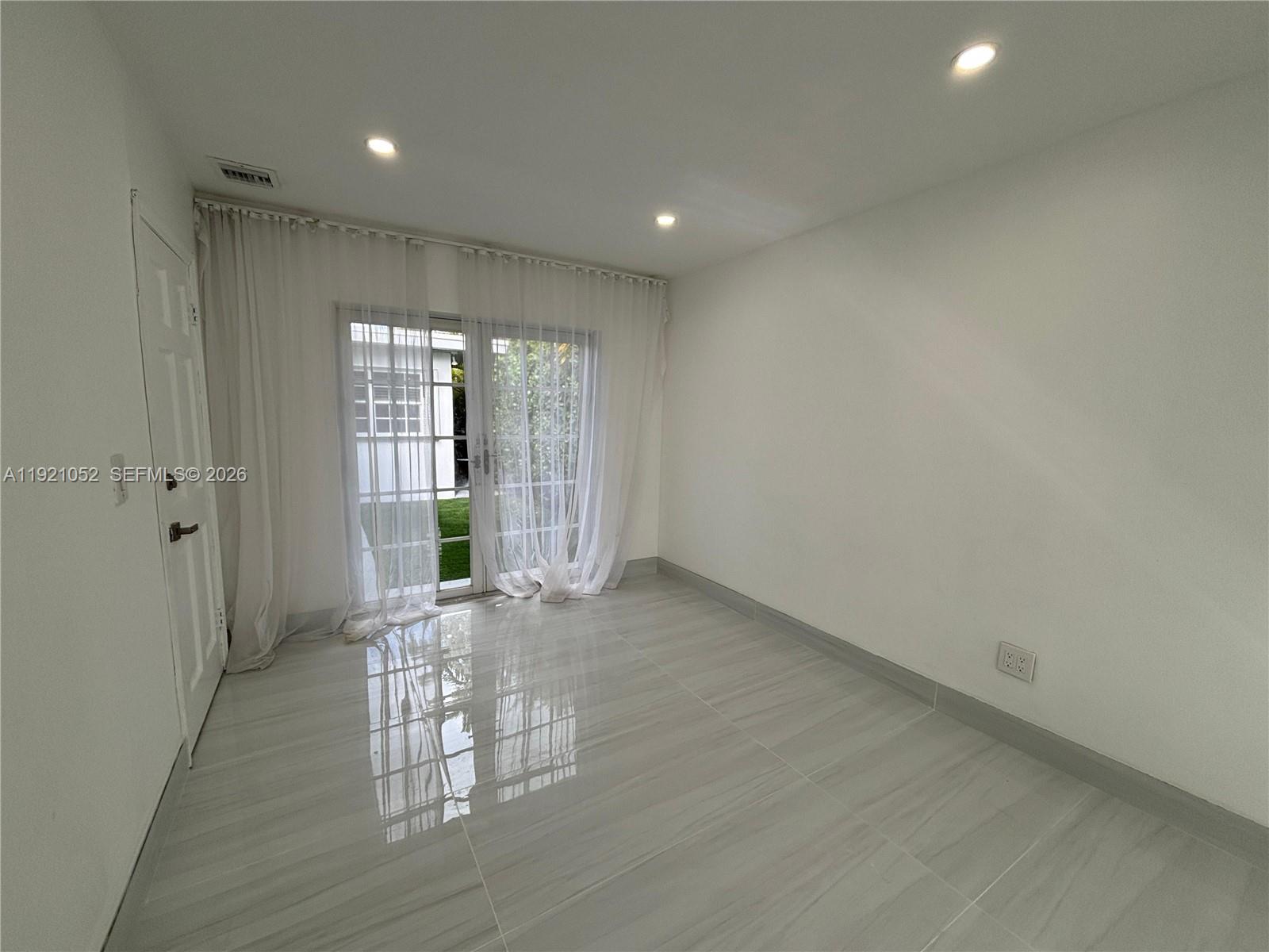 725 91st Street Surfside, FL 33154 - Photo 11 of 32 a view of an empty room with wooden floor and a window