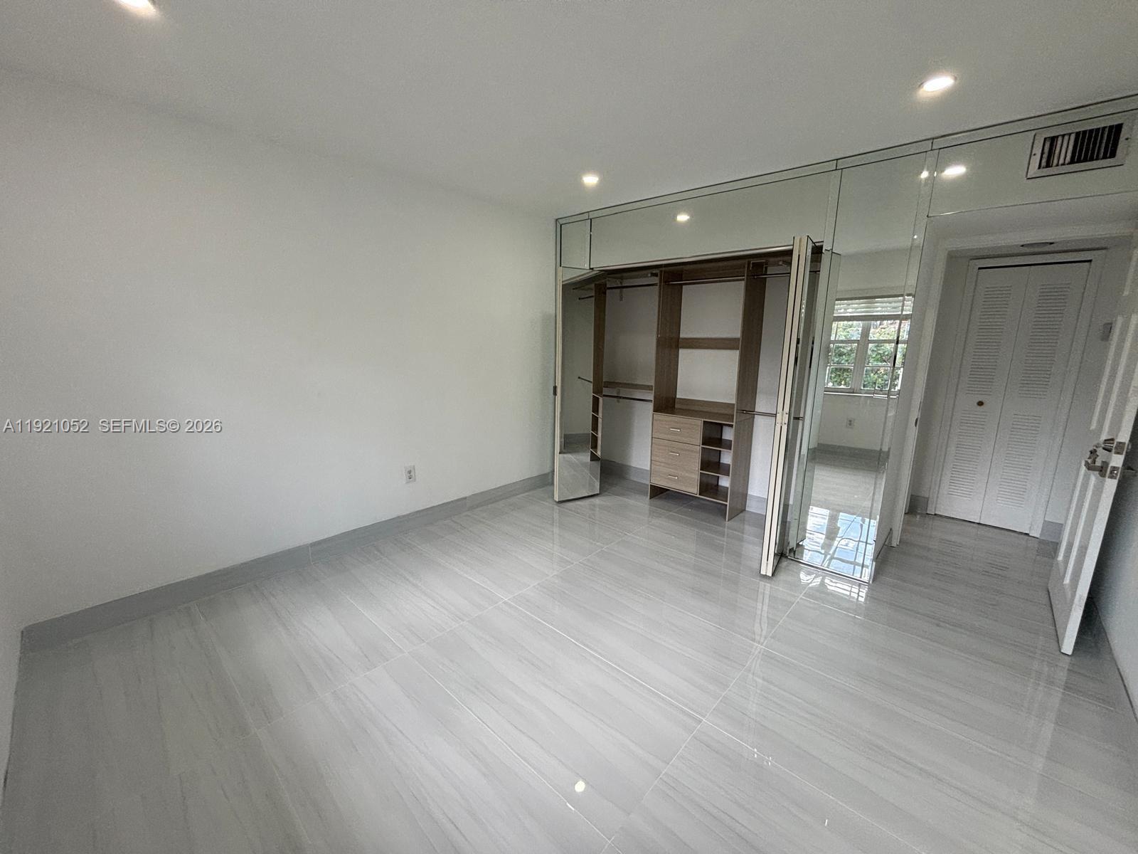 725 91st Street Surfside, FL 33154 - Photo 13 of 32 an empty room with wooden floor and windows